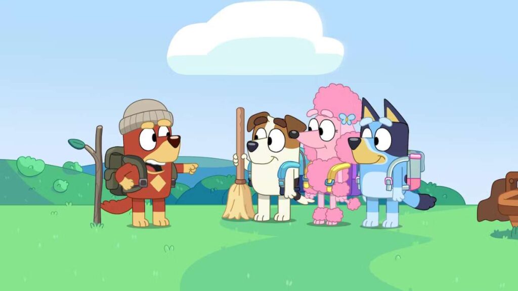 Four character  from Bluey  in hiking outfits standing on a grassy hill with a blue sky.